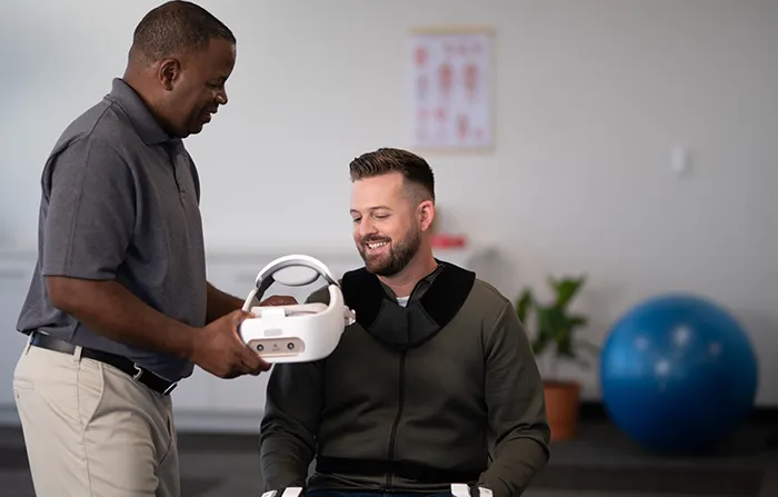 physical therapist hands a user the REAL System VR headset for rehabilitation