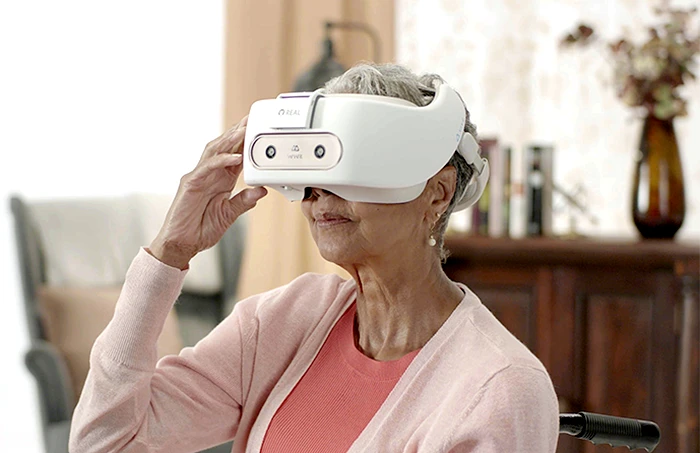 An elderly woman using REAL System's VR headset for sharpening mental skills