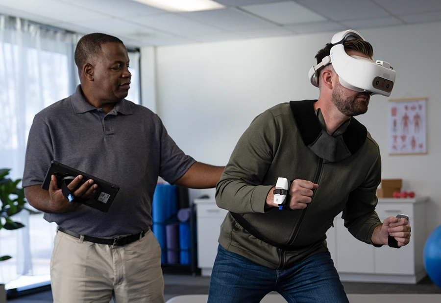 A physical therapist directs a user in a REAL System VR headset for rehabilitation