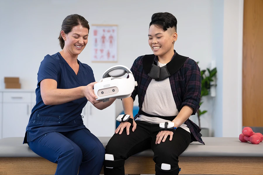 Physical therapist handing a REAL System VR headset to user for rehabilitation