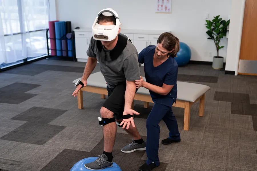 Physical therapist stabilizes client wearing the REAL System VR headset
