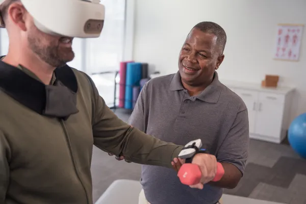 Physical Therapist aiding a client who is wearing a REAL System VR headset for rehabilitation